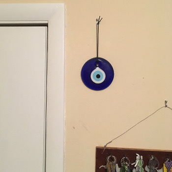 Glass blue evil-eye icon, by door with rack of keys below